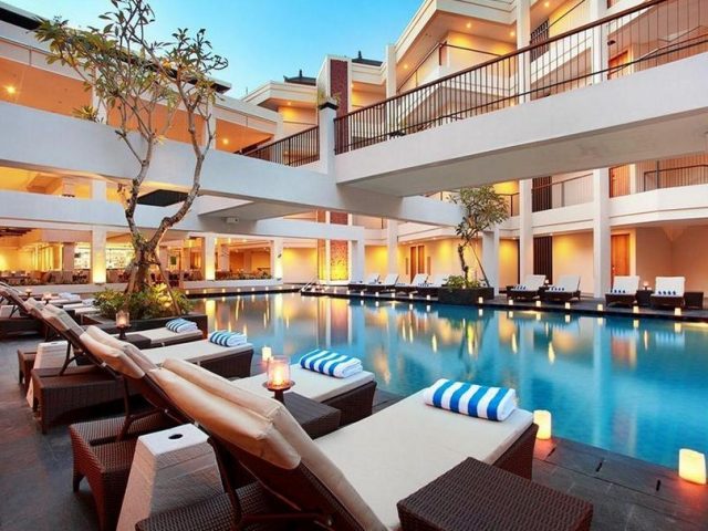 Pool with lounge seating below the multi-storey hotel at Vouk Hotel & Suites