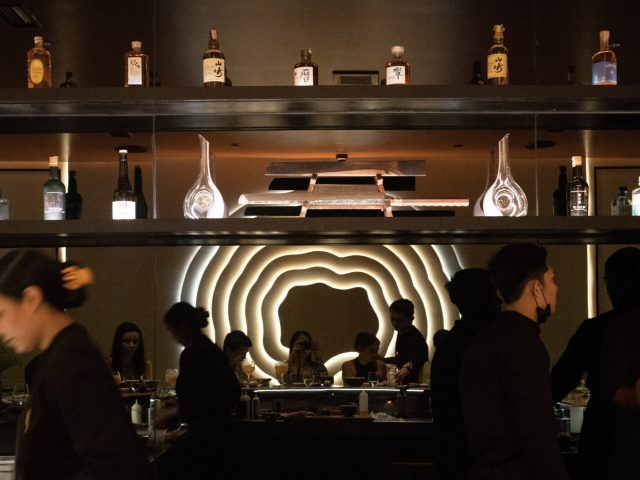 Bar with a wine display and dramatic lighting at Miss Fish restaurant