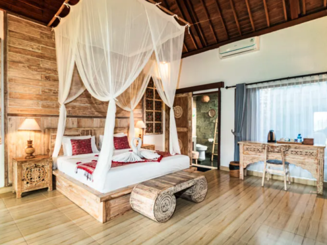 Villa bedroom with a four-poster bed opening to a garden at Taro Hotel