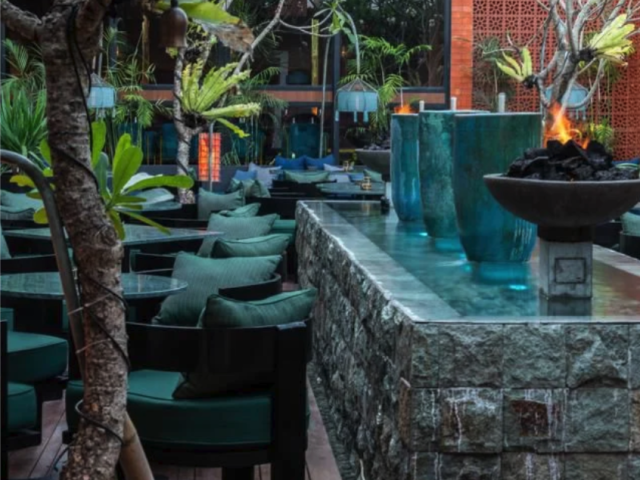 Textured stone wall with greenery and blue seating at Jade restaurant